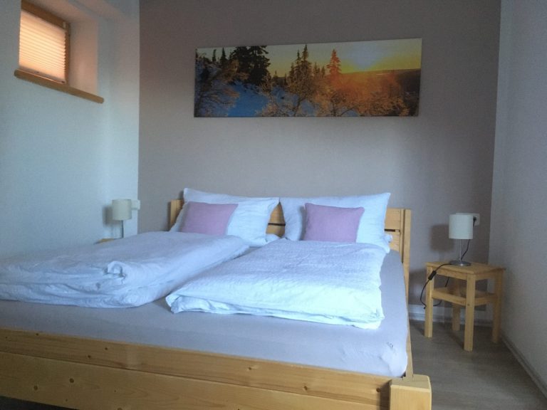 Gemütliches Schlafzimmer mit Holzelementen und Baumwollbettwäsche in der Ferienwohnung Neyer in Steibis – Raum zum Durchatmen im Allgäu.